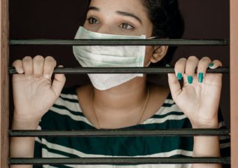 woman in green and white stripe shirt covering her face with white mask